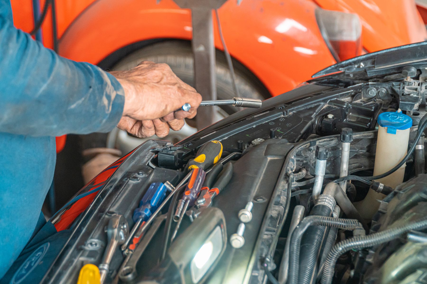 Mechanic using a tool on an engine under the bonnet